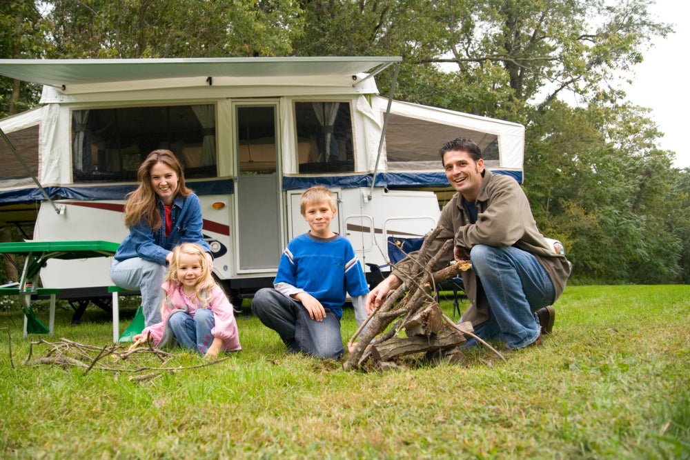 Family sitting on the grass in front of their camper trailer