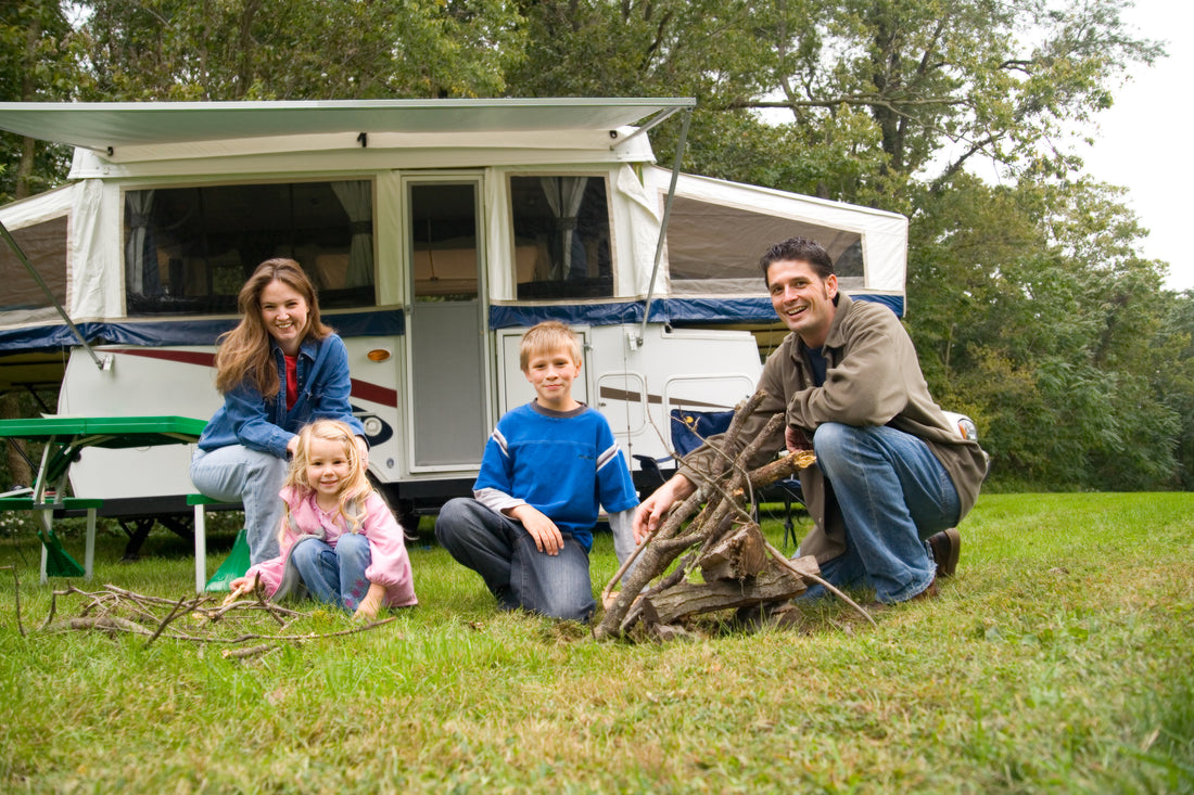 Family sitting on the grass outside their camper trailer
