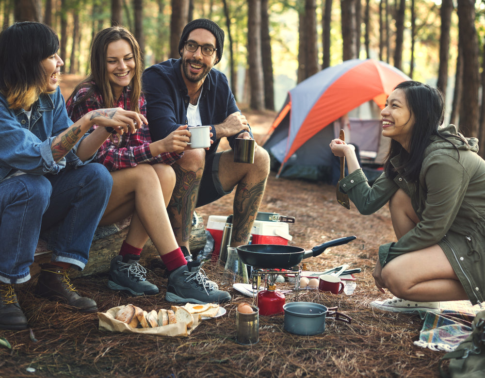 Camping - A group sits outside a tent around a portable cooker